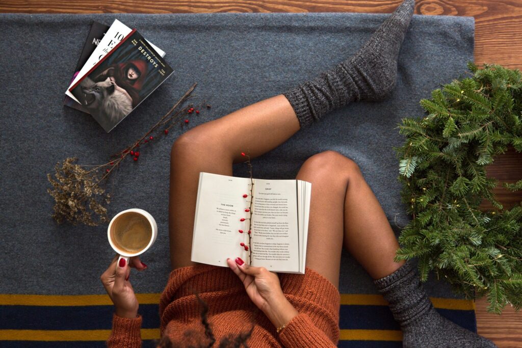 Woman's legs in warm socks, readying surrounded by festive items on a Winter evening