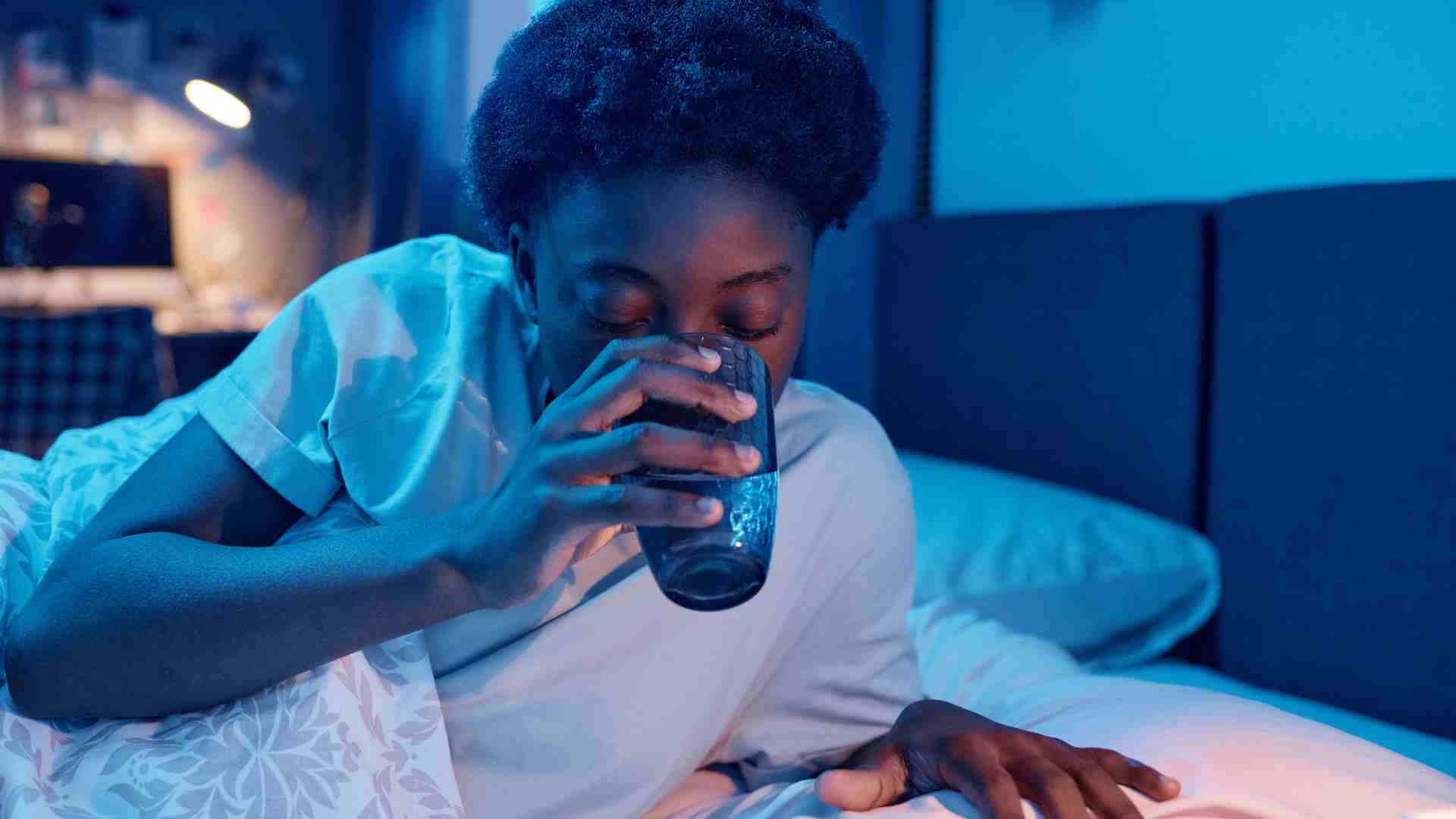 Person sipping a drink in bed
