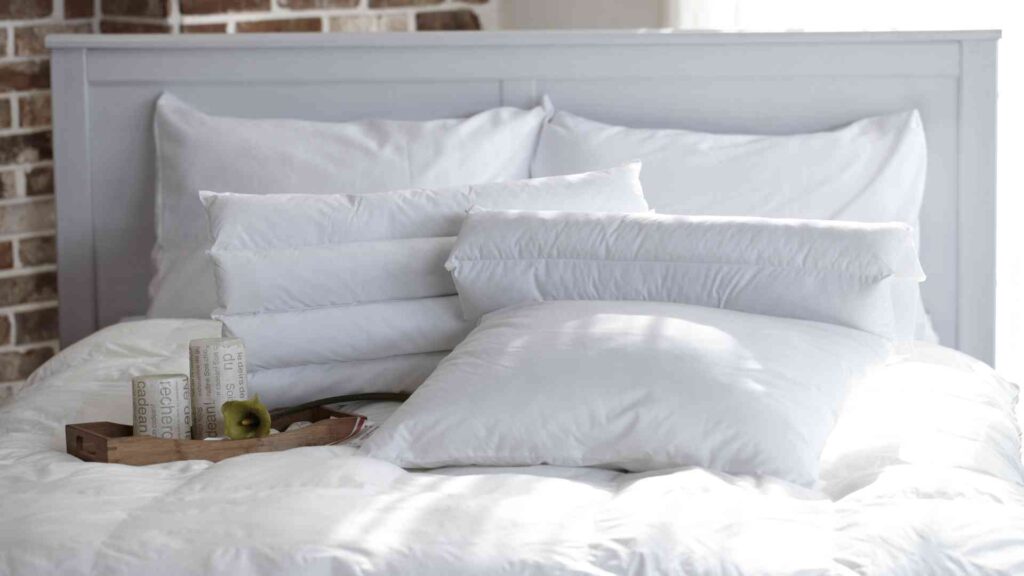 Pile of different types of pillows on a bed