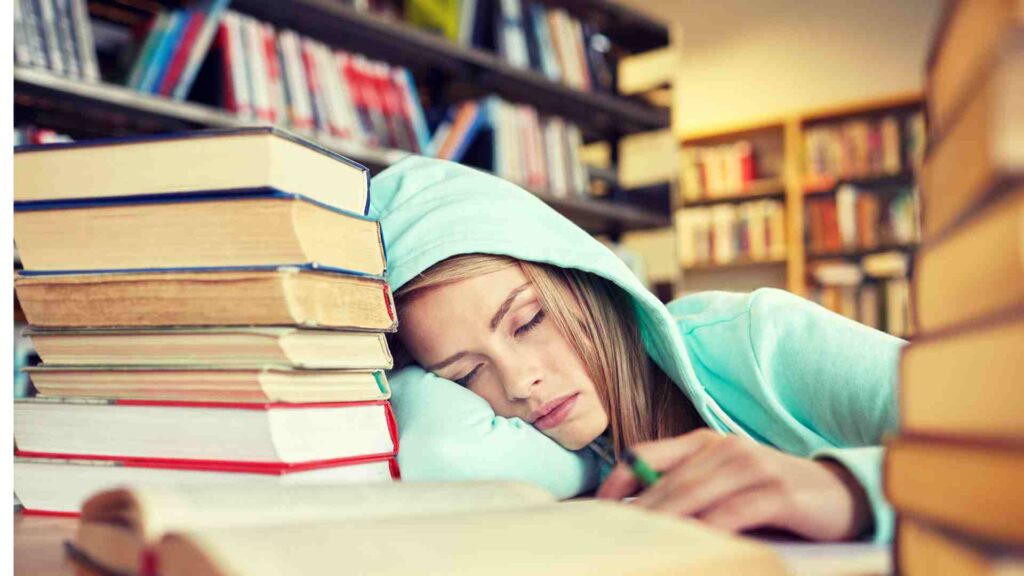 Teenage girl asleep whilst studying in her hoodie